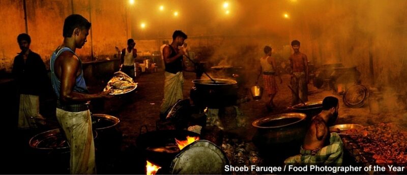 Pessoas com prato de alimentos em uma cozinha envolta de cortina de fumaça, foto premiada de Shoeb